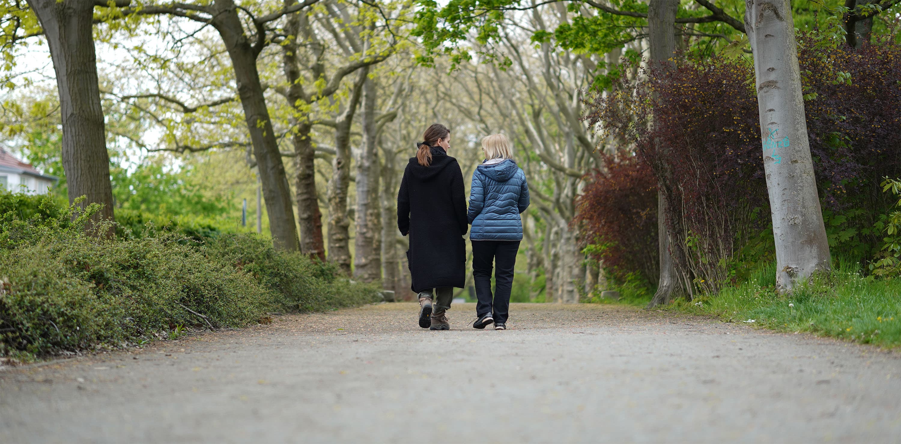 Zwei Frauen gehen zusammen im Park mit Bäumen